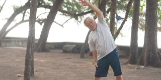 4K快乐的亚洲老人早上在海滩上锻炼。