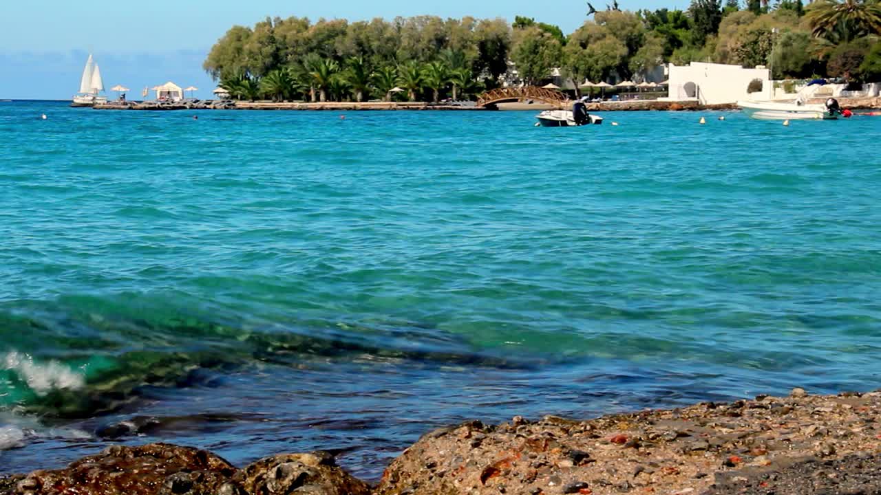 温暖的海岸在壮丽的蔚蓝海湾，小船和快艇在波浪中摇摆，一艘游艇和一艘轮船在远处航行