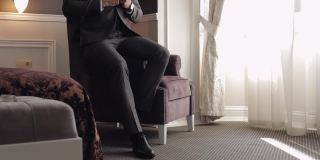 英俊的新郎商人在家里的客厅里穿着灰色夹克，白衬衫配黑领带