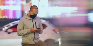 亚洲男子戴着口罩，晚上用智能手机等出租车或优步。