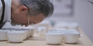 3名亚洲华裔男咖啡师品酒师表演杯咖啡，品尝杯咖啡后在剪贴板上写下