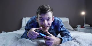 兴奋开朗的年轻人在家里用操纵杆玩电子游戏。男玩家使用无线控制器在电视上玩网络游戏。数字技术