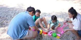 4K幸福的亚洲家庭和沙滩玩具一起在沙滩上玩沙子