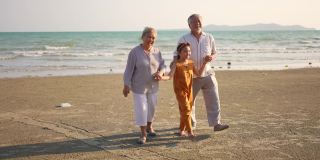 在阳光明媚的日子里，爷爷奶奶和孙女一起在海滩上散步