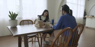 一对亚洲年轻夫妇在客厅的桌子上享受着外卖