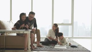 一个年轻的亚洲华人家庭周末在家里的客厅公寓里做作业和画画视频素材模板下载