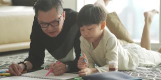 亚洲华人年轻的父亲和儿子周末在家里客厅公寓里画画，享受亲子时光
