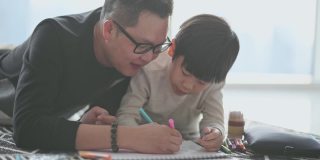 亚洲华人年轻的父亲和儿子周末在家里客厅公寓里画画，享受亲子时光