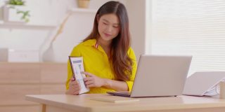 快乐的年轻亚洲女商人戴着黄色和头戴耳机在网上视频电话会议上与她的业务团队展示销售报告，商业启动概念