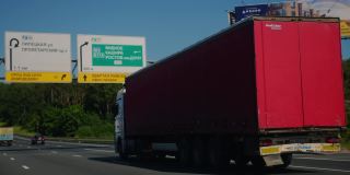 带着货物拖车的半挂车行驶在公路上。卡车是白色的，货运拖车是红色的。使用黑魔法袖珍电影相机6K拍摄