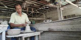 慢镜头，亚洲华人活跃的高级陶工在他的工作室用旋转的陶轮工作