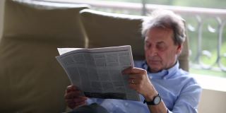 老人在看报纸。年长的商人读传统新闻