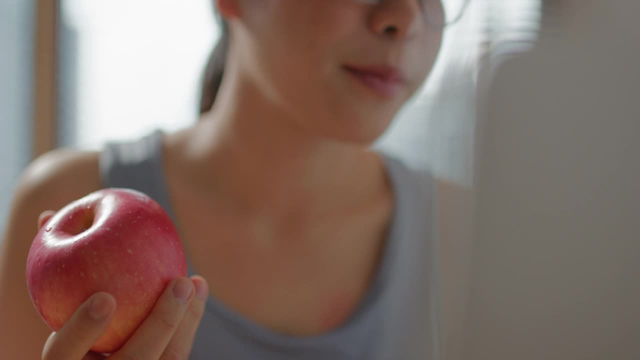 快乐的女人在家锻炼后吃一个苹果