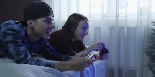 朋友们用操纵杆玩电子游戏。快乐兴奋的情侣在家里用无线控制器玩在线视频游戏，一起玩得很开心。夫妻待在家里的概念