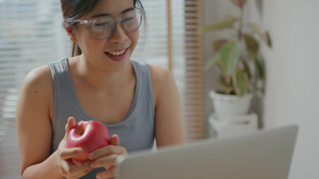 快乐的女人在家锻炼后吃一个苹果