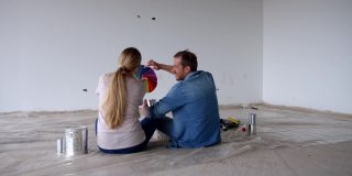 一对拉丁美洲夫妇坐在地板上为他们新家的墙壁选择颜色