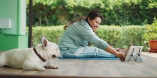 一个健康的女人早上和法国斗牛犬一起练习瑜伽。