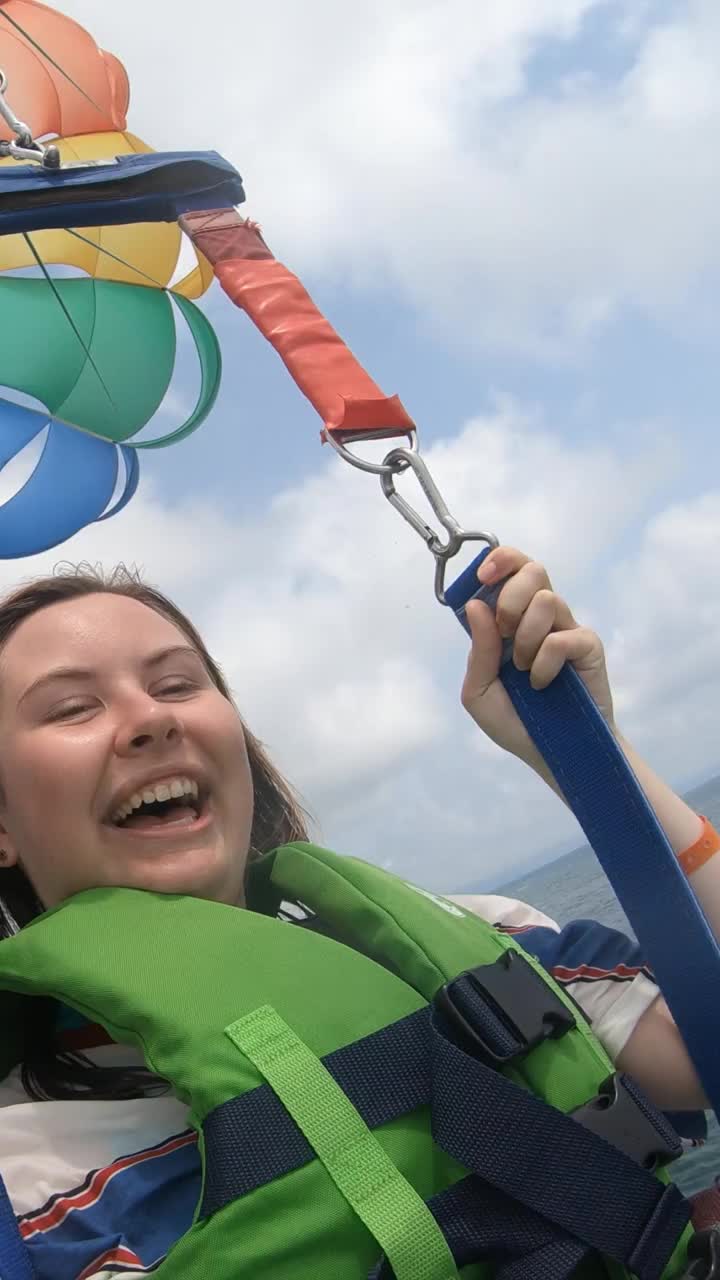 年轻女子带着降落伞在海上飞行