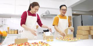 4K亚洲夫妇面包店店主包装面包房在快递箱一起。