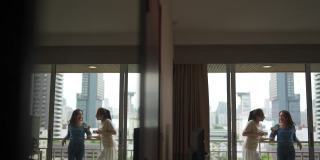 4K亚洲女性朋友们站在阳台上一边喝着咖啡一边聊天。