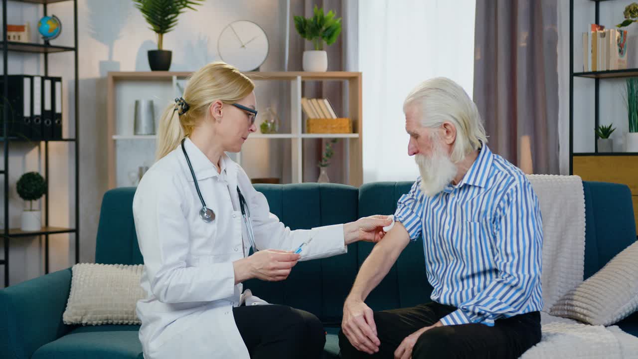 有魅力的积极护理技术熟练的女医务工作者在家访期间为白发大胡子老人注射
