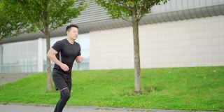年轻的亚洲男子在城市和公园的街道上跑步，享受健身手表