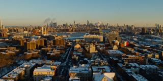 美国纽约市布鲁克林海军造船厂和威廉斯堡住宅区上空的曼哈顿，阳光明媚的冬日黎明。无人机视频与复杂的电影向后平移相机运动。