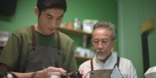 亚洲华人男咖啡师咖啡店老板正在和他的员工进行冷煮咖啡点滴培训