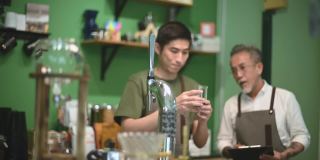 亚洲华人男咖啡师咖啡店老板正在和他的员工进行冷煮咖啡点滴培训
