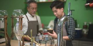 亚洲华人资深男咖啡师老板在他的咖啡厅吧台品尝教练的拿铁咖啡时很满意