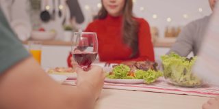 亚洲幸福家庭，年轻夫妇一起在家里举办圣诞晚会。漂亮迷人的父母在餐桌上碰杯，吃晚餐庆祝圣诞节的晚上在家里。