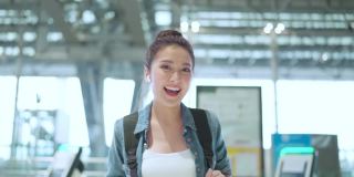 封城结束后，幸福女性再次享受旅行，年轻的亚洲女性在机场候机楼用清新爽朗的背包休闲布微笑着挥手欢迎旅行理念