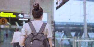 在机场候机楼的自动扶梯上背着背包和行李箱的亚洲女性乘客背影，新冠肺炎封锁结束后的旅行生活方式