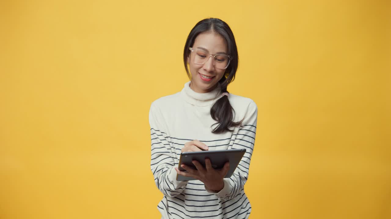 快乐迷人的亚洲女学生手持平板电脑，手指着书库享受电子书网上购物。