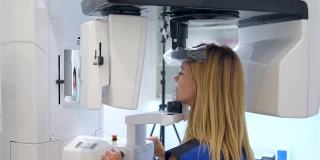 年轻女病人站在牙科x光机前进行牙科放射照相