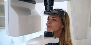 一位女性患者站在牙科计算机断层扫描仪前。