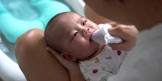 亚洲母亲用抹布清洁婴儿的嘴