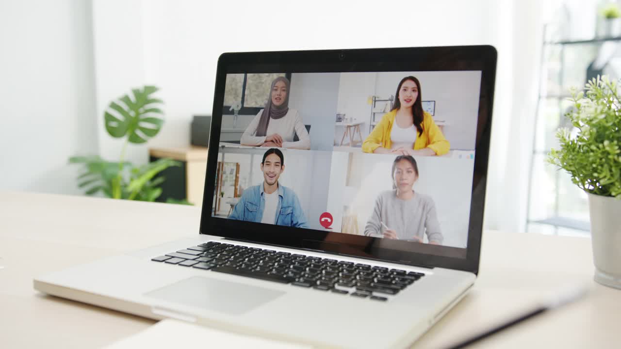 亚洲女商人使用笔记本电脑与同事在视频电话会议的计划，而工作在家里的客厅。