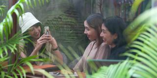 一群亚洲女性朋友在咖啡店见面，一起用智能手机自拍