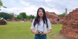 开朗美丽的年轻亚洲背包客博主女人随意带着相机微笑着在古城宝塔周围旅行。