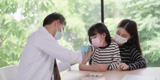 感受少女对针头的恐惧，亚洲资深男医生戴着卫生口罩在亚洲患者的手臂上注射疫苗，一个孩子带着姐姐像朋友一样过来
