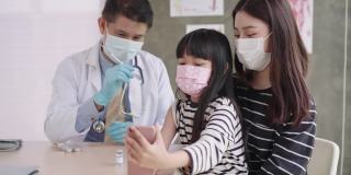 一名儿童在接种新冠疫苗的瞬间，少女的手臂从戴着卫生脸的中间人医生手中获得，带着积极的情绪自拍获得免疫剂量。