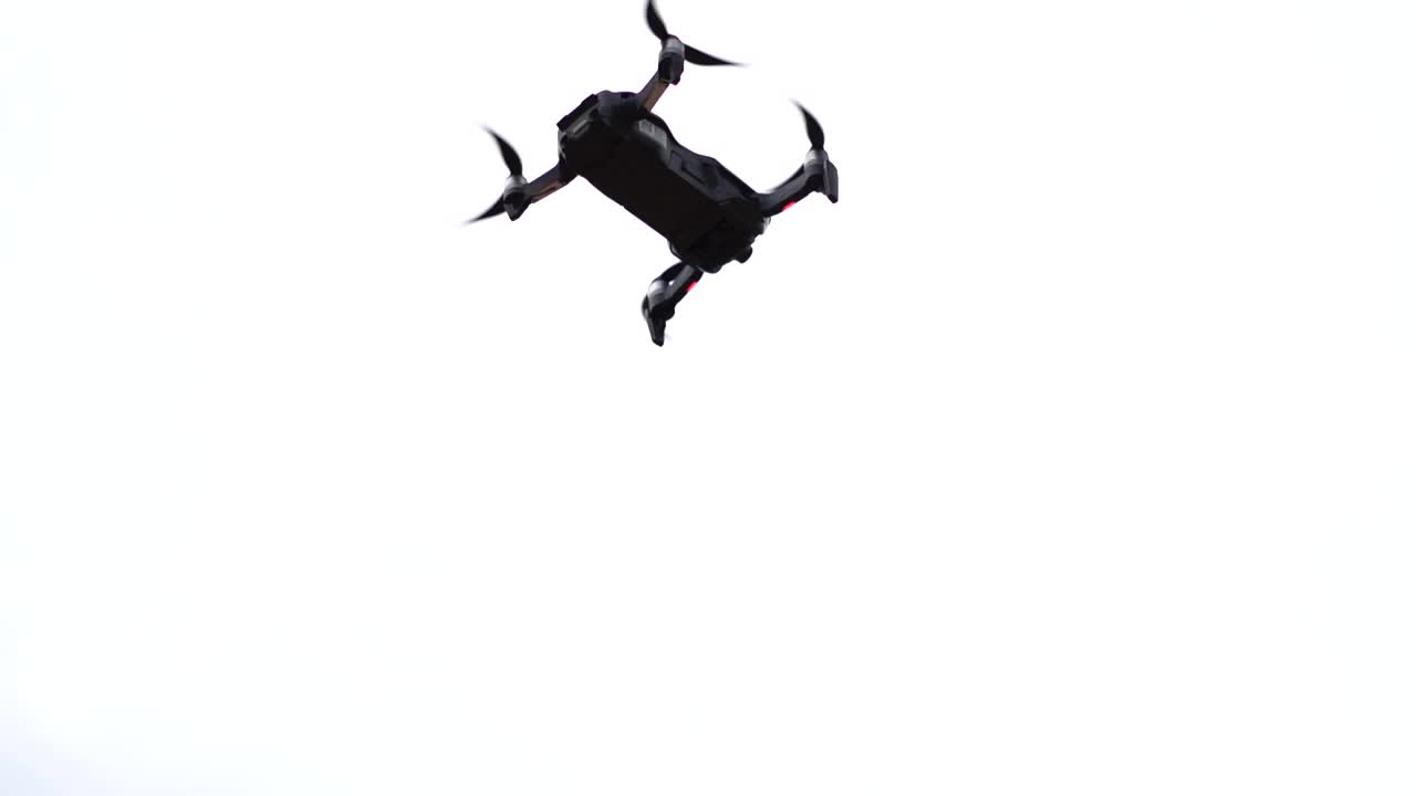 低角度拍摄无人机四旋翼与数码相机在蓝天，与云。无人机在云层背景的天空中高速飞行