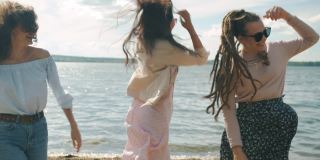 女性朋友们穿着时髦的夏装在海滩上跳舞，一起享受周末