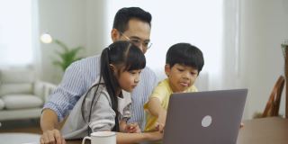 亚洲父亲和孩子们一起使用笔记本电脑