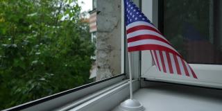 美国国旗立在架子上窗户上，在风中飘动。
