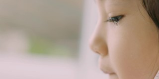 可爱的亚洲小女孩的临场临场侧视在哭泣，通过她的眼睛和美丽的肤色来表达人们的悲伤、不快乐、沮丧和悲伤。
