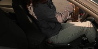 坐在车里的女人把拐杖放在副驾驶座位上，关上车门并系好安全带。身体残疾的