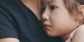脸近4K可爱的5岁亚洲女孩在妈妈抱着哭的悲伤显示美丽的脸表达情感。是父母用爱呵护孩子。