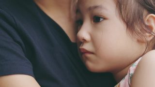 脸近4K可爱的5岁亚洲女孩在妈妈抱着哭的悲伤显示美丽的脸表达情感。是父母用爱呵护孩子。视频素材模板下载